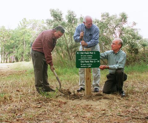 A photo of the 3 professors who helped found the natural area installing a sign