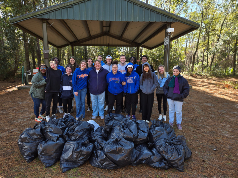 a group of student volunteers standing in front of bags of trash